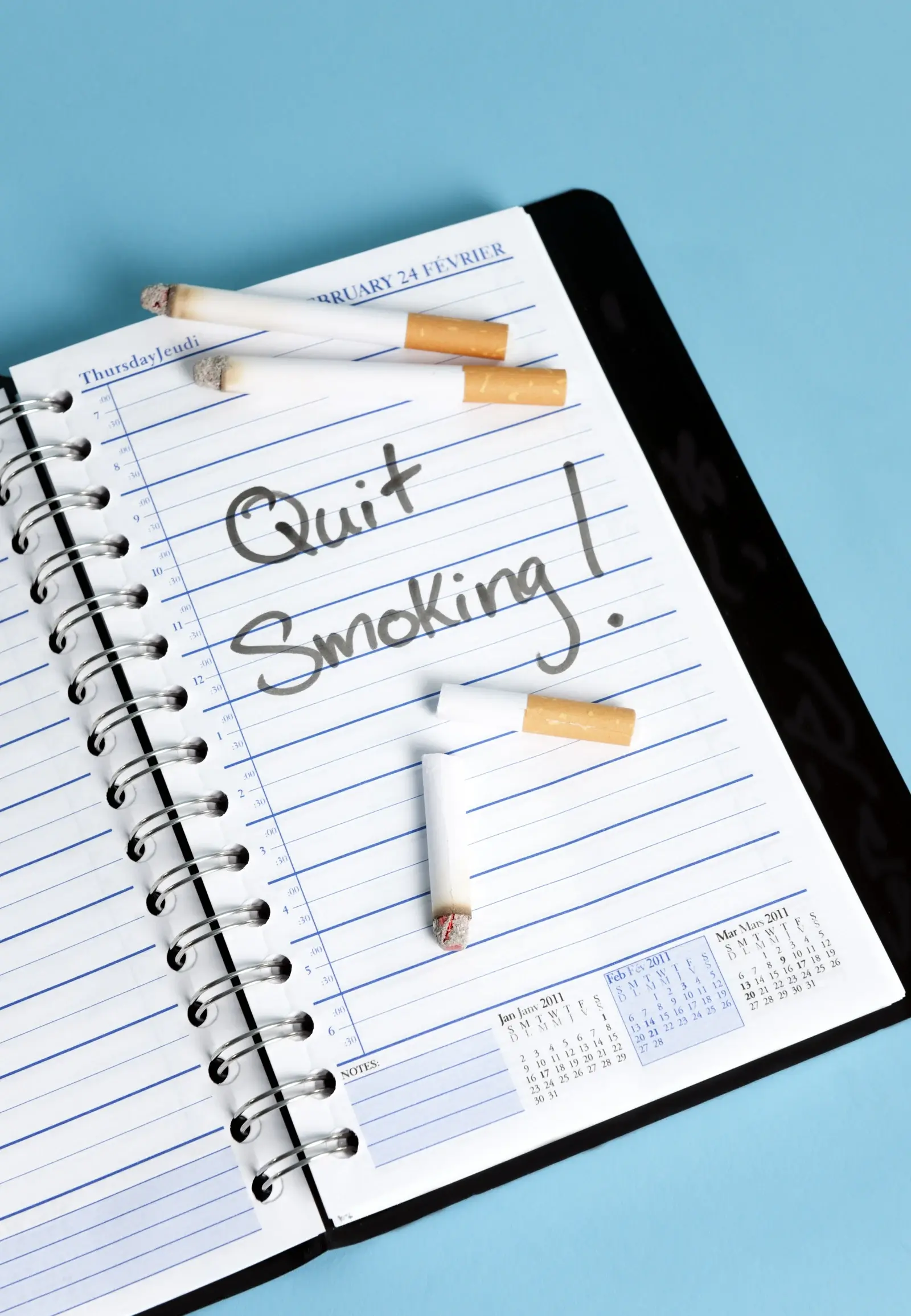Quit smoking written in a diary with broken cigarettes on the page, marking the start of the body’s recovery in the weeks after quitting